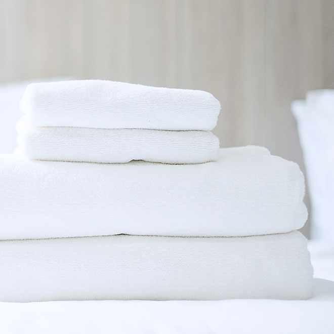 Stack of white towel and Bathrobe on bed in luxury hotel or resort. Laundry, Relax, holiday, spa, massage and vacation concepts
